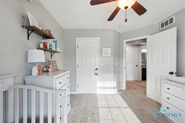 bedroom featuring light colored carpet, a nursery area, and ceiling fan