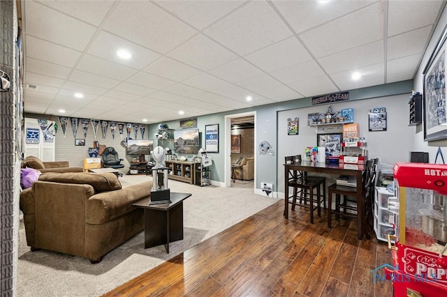 living room featuring a drop ceiling and dark wood-type flooring