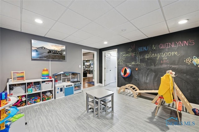 recreation room with a drop ceiling and hardwood / wood-style flooring