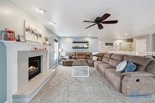 living room with a brick fireplace, carpet flooring, and ceiling fan