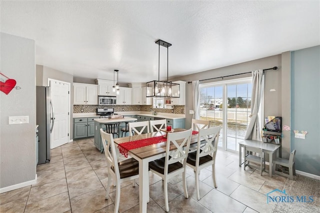 tiled dining space with a chandelier and a textured ceiling