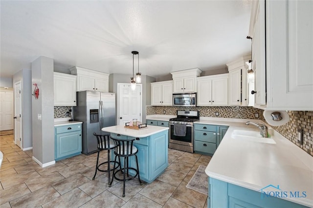 kitchen featuring blue cabinetry, a breakfast bar, white cabinetry, a kitchen island, and stainless steel appliances