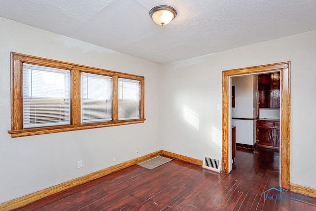 empty room with dark hardwood / wood-style floors and a textured ceiling