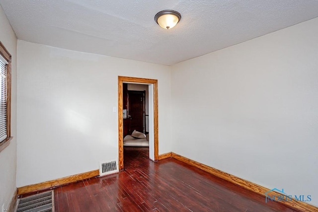 unfurnished room featuring dark hardwood / wood-style floors and a textured ceiling