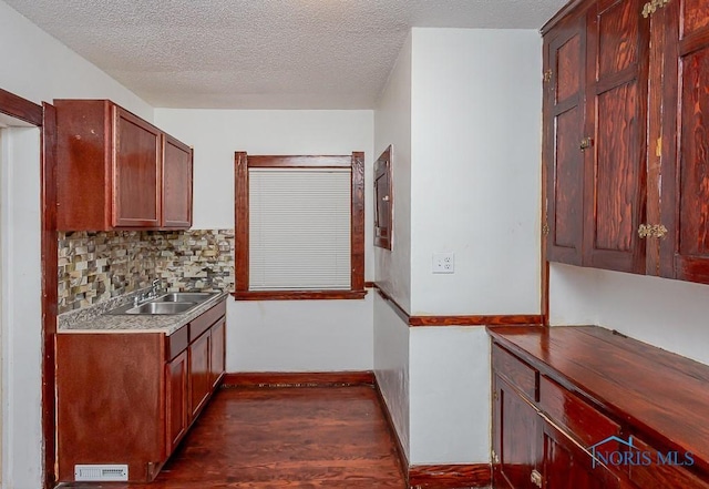 kitchen featuring dark hardwood / wood-style flooring, sink, a textured ceiling, and backsplash