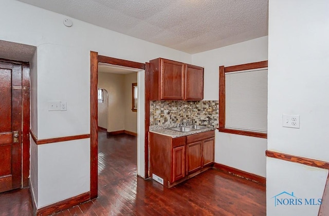 kitchen with sink, decorative backsplash, dark wood-type flooring, and a textured ceiling