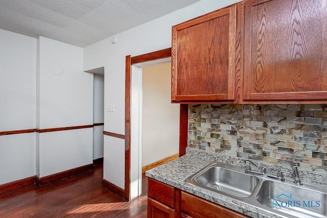 kitchen with tasteful backsplash, sink, dark hardwood / wood-style floors, and a textured ceiling