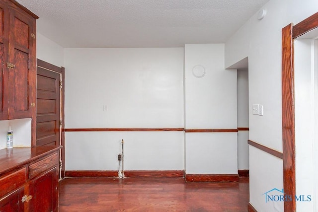 unfurnished room with dark hardwood / wood-style floors and a textured ceiling