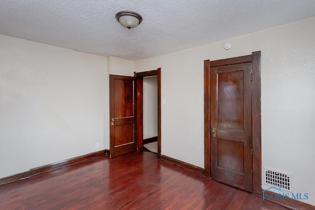 spare room featuring dark hardwood / wood-style floors and a textured ceiling