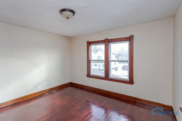 empty room with hardwood / wood-style flooring and a textured ceiling