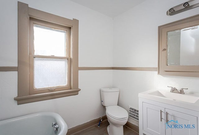 bathroom featuring vanity, toilet, hardwood / wood-style floors, and a washtub