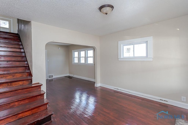 spare room featuring dark wood-type flooring and a textured ceiling