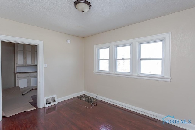 unfurnished room with dark hardwood / wood-style flooring and a textured ceiling