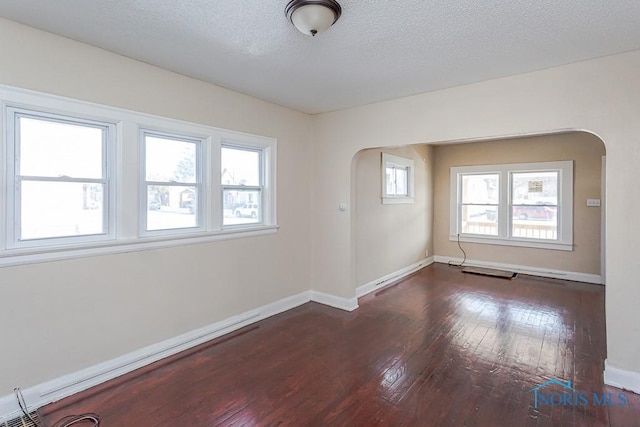 spare room with a textured ceiling and dark hardwood / wood-style flooring