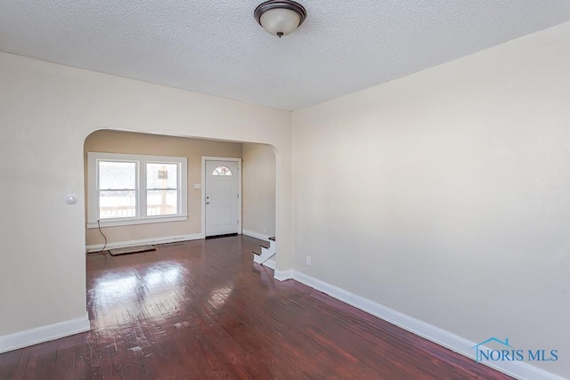 spare room with dark hardwood / wood-style floors and a textured ceiling