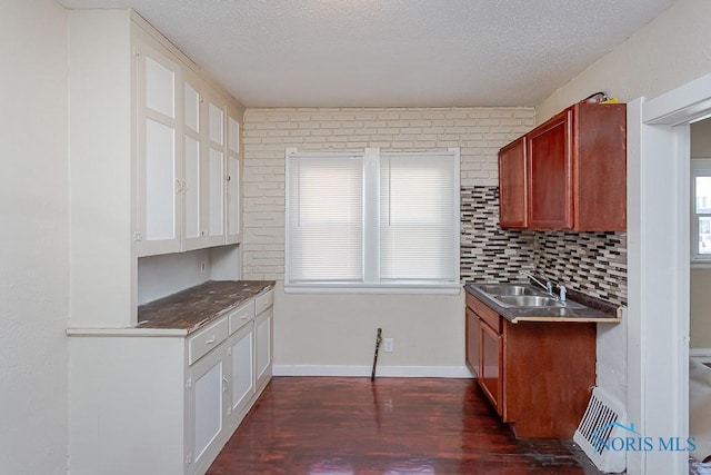 kitchen with tasteful backsplash, sink, dark hardwood / wood-style flooring, stainless steel counters, and a textured ceiling