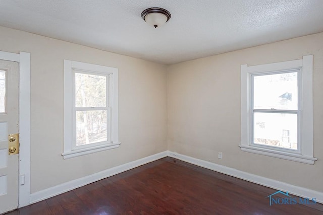 unfurnished room featuring dark wood-type flooring, a wealth of natural light, and a textured ceiling