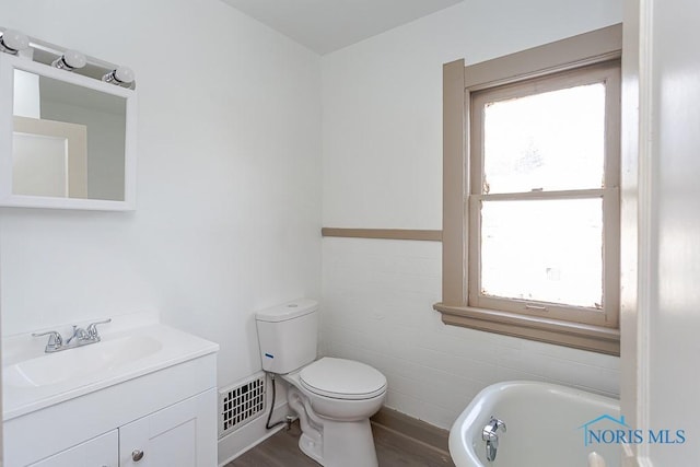 bathroom featuring wood-type flooring, toilet, a bathing tub, and vanity