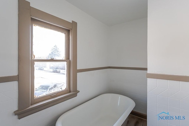 bathroom with tile walls and a tub to relax in