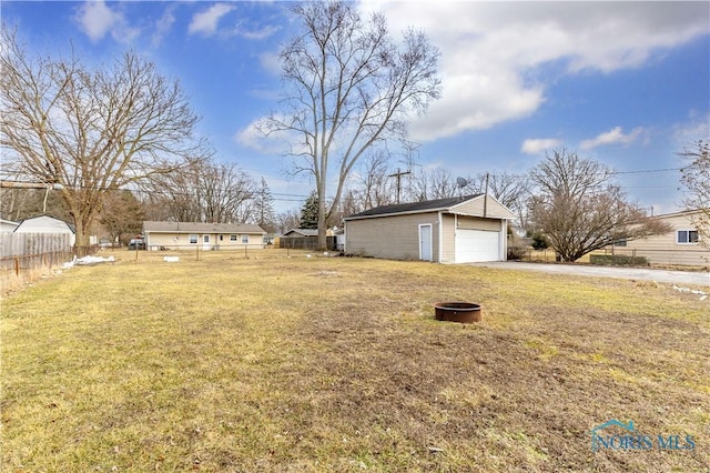 view of yard featuring a detached garage, fence, and an outdoor structure