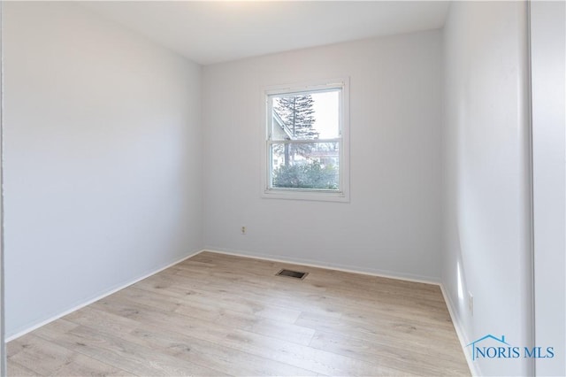 empty room featuring light wood finished floors, baseboards, and visible vents