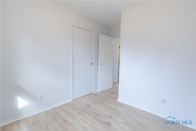 spare room with baseboards and wood finished floors