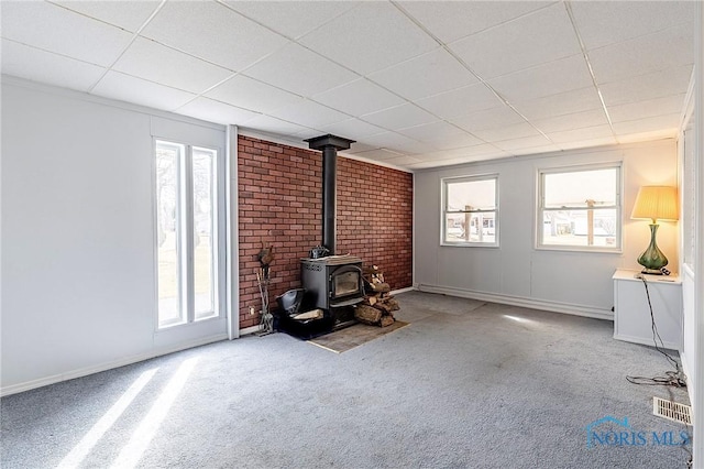 unfurnished living room featuring visible vents, carpet, a wood stove, and baseboards