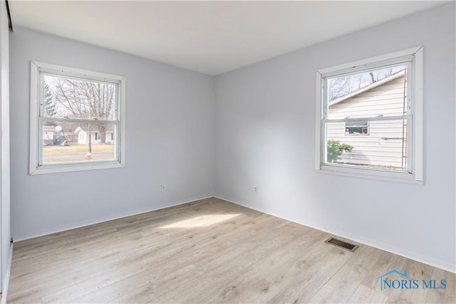 empty room featuring light wood-style floors and visible vents