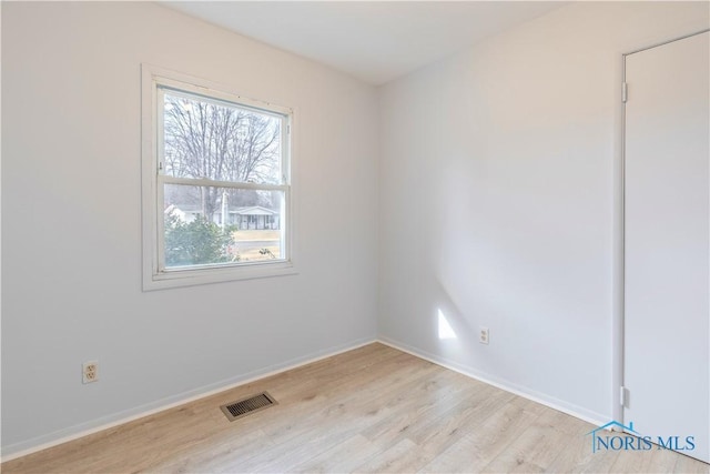 empty room with light wood-type flooring, visible vents, and baseboards