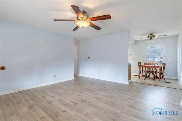 empty room featuring light wood finished floors, baseboards, and a ceiling fan