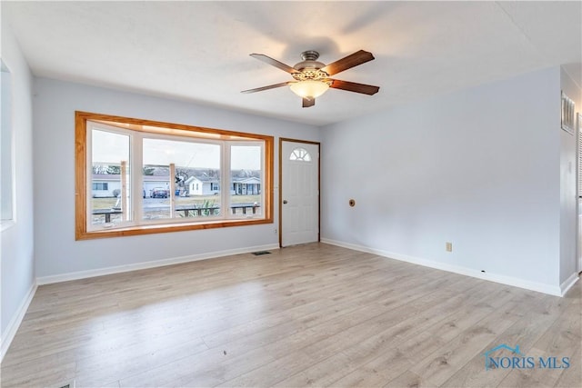 empty room featuring ceiling fan, light wood-type flooring, visible vents, and baseboards