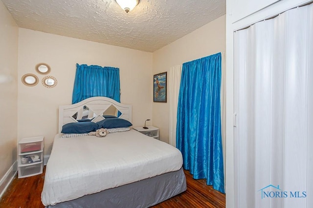 bedroom featuring dark wood-type flooring and a textured ceiling