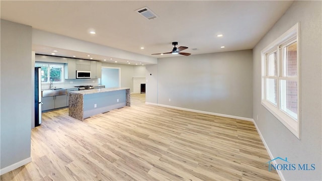 kitchen featuring white cabinetry, light hardwood / wood-style flooring, appliances with stainless steel finishes, a kitchen island, and ceiling fan