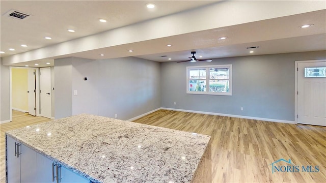 kitchen featuring a kitchen island, plenty of natural light, light wood-type flooring, and light stone counters