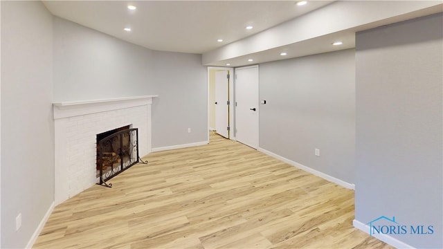 unfurnished living room featuring a brick fireplace and light hardwood / wood-style flooring