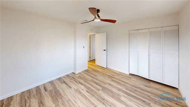 unfurnished bedroom featuring ceiling fan, a closet, and light wood-type flooring