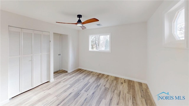 unfurnished bedroom with ceiling fan, a closet, multiple windows, and light hardwood / wood-style flooring