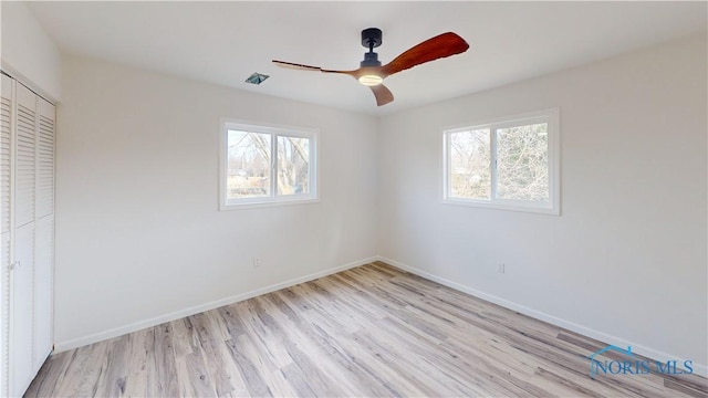 unfurnished bedroom featuring multiple windows, a closet, ceiling fan, and light wood-type flooring