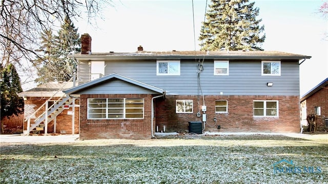 rear view of house featuring cooling unit and a yard