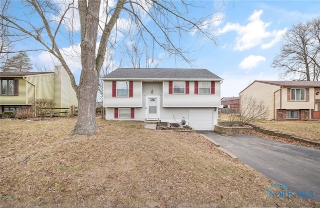 split foyer home featuring a garage and a front yard