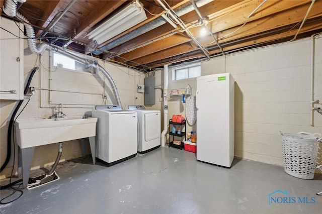 basement with white refrigerator, a healthy amount of sunlight, electric panel, and washer and dryer