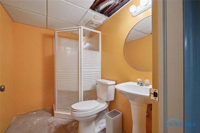 bathroom featuring a drop ceiling, a shower with shower door, and toilet