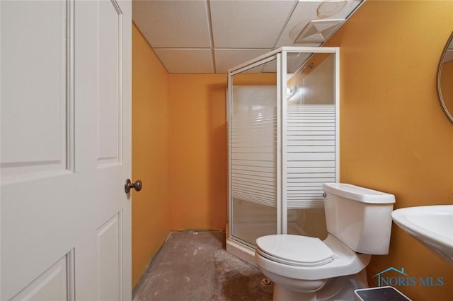 bathroom with toilet, a shower with door, and a drop ceiling