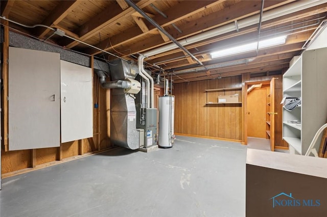 basement with water heater, heating unit, and wooden walls