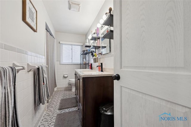 bathroom featuring vanity, tile patterned floors, toilet, and tile walls