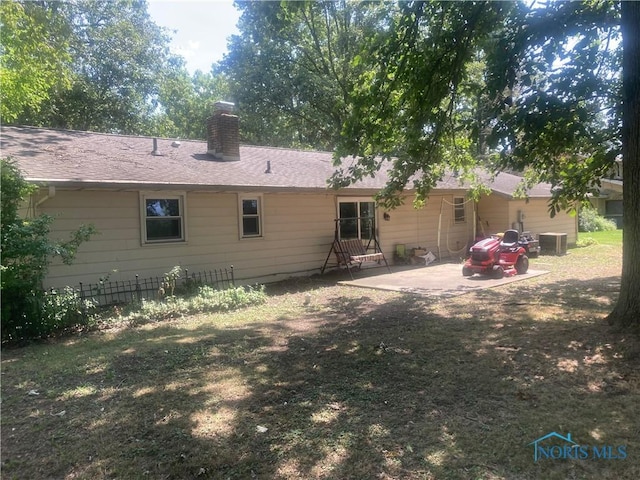 back of property with a patio area, central air condition unit, and a lawn