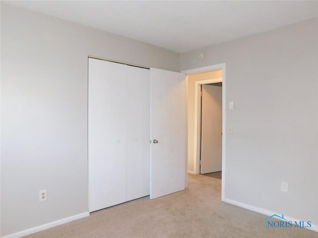 unfurnished bedroom featuring light colored carpet and a closet