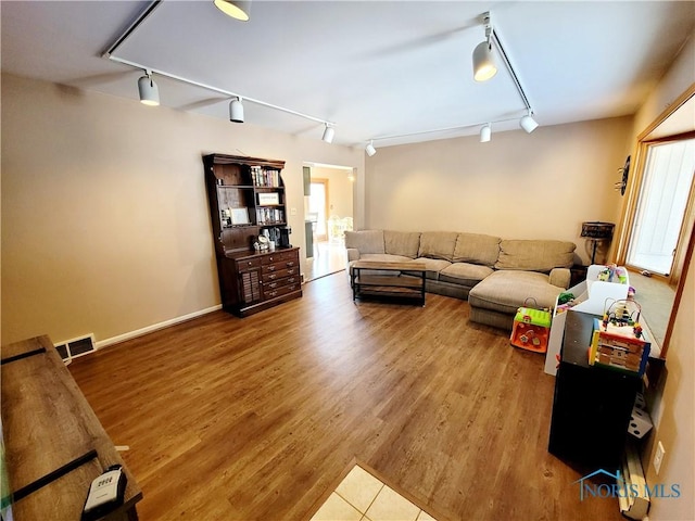 living room with a healthy amount of sunlight, wood-type flooring, and rail lighting