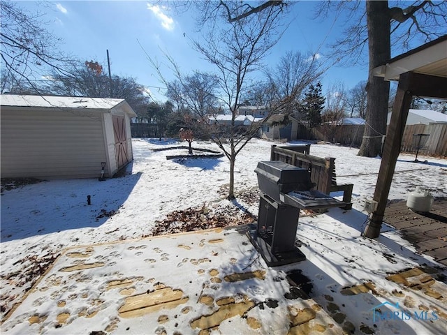 snowy yard with a storage shed