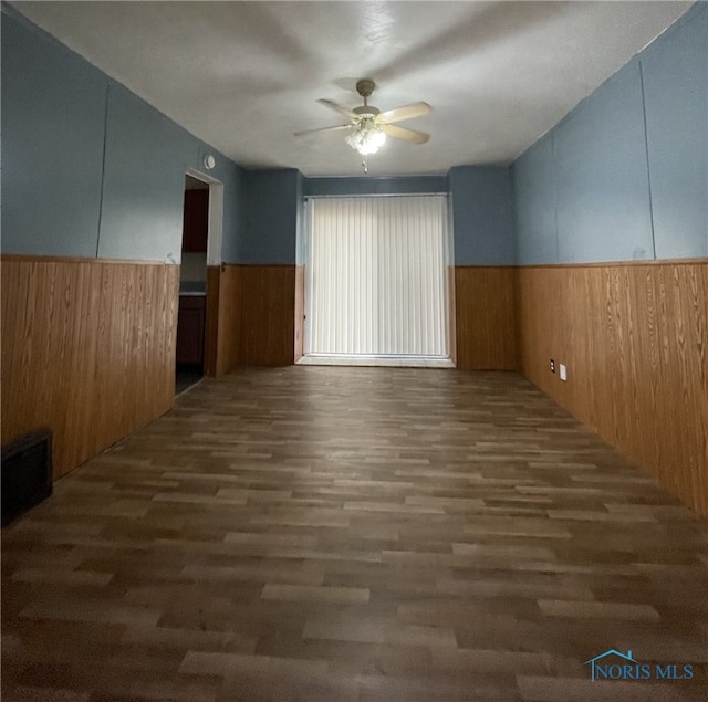 spare room with dark hardwood / wood-style floors, ceiling fan, and wood walls